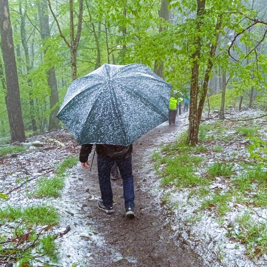 Wanderer im Schneeregen mit Regenschirm
