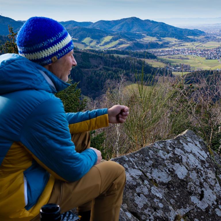 Wanderer sitzt auf einem Höhenweg im Schwarzwald und blickt ins Tal