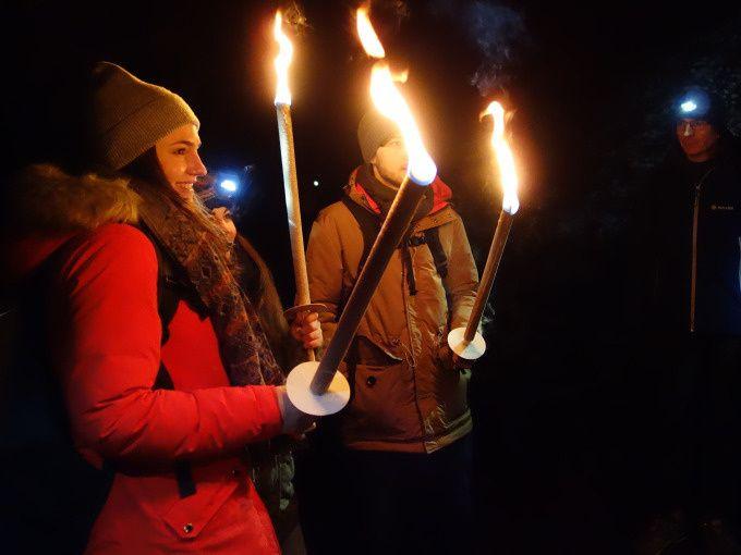 Gruppe mit Fackeln bei einer nächtlichen Winterwanderung in der Ravennaschlucht im Schwarzwald