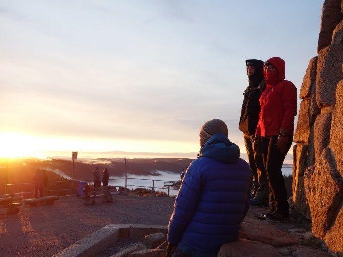 Wanderer genießen den Sonnenaufgang auf dem Feldberg mit Blick über das nebelverhangene Tal im Schwarzwald