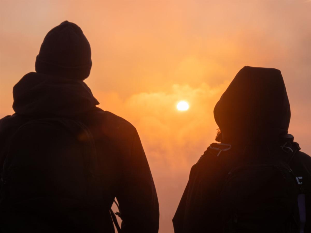 Zwei Wanderer zum Sonnenaufgang am Feldberg im Gegenlicht