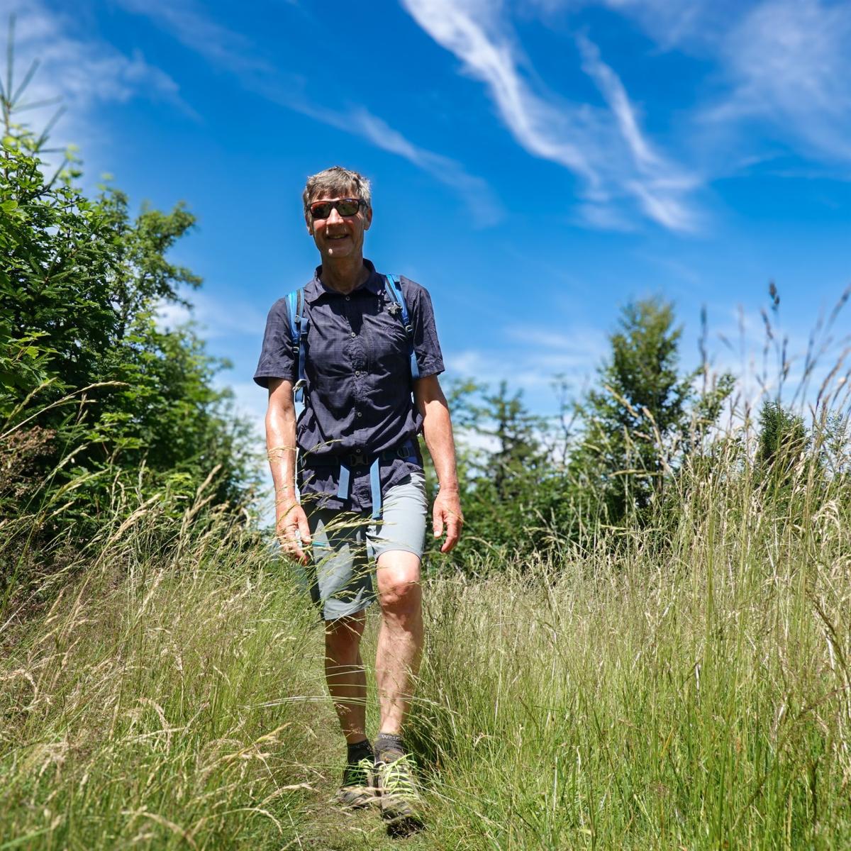 Wanderer auf schmalem Naturpfad im Schwarzwald bei sonnigem Wetter