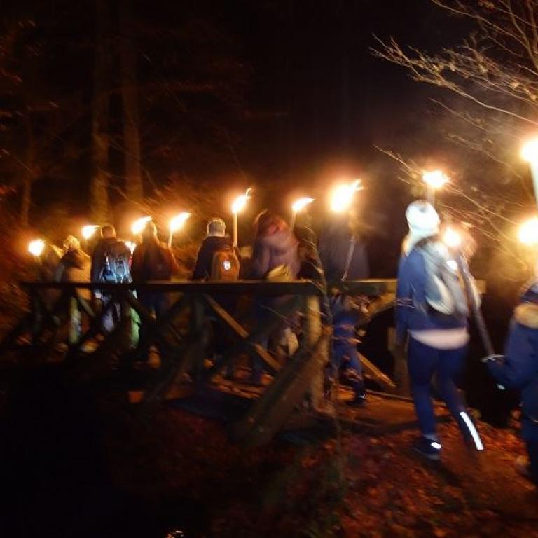 Fackelwandergruppe auf Brücke