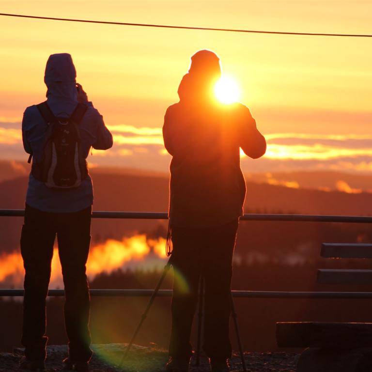 Zwei Personen im Sonnenaufgang Gegenlicht